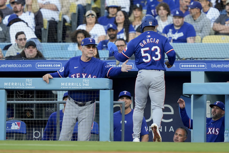 Texas Rangers' Adolis Garcia, right, celebrates with manager Bruce Bochy after scoring off a single hit by Wyatt Langord during the first inning of a baseball game against the Los Angeles Dodgers, Thursday, June 13, 2024, in Los Angeles. (AP Photo/Ryan Sun)