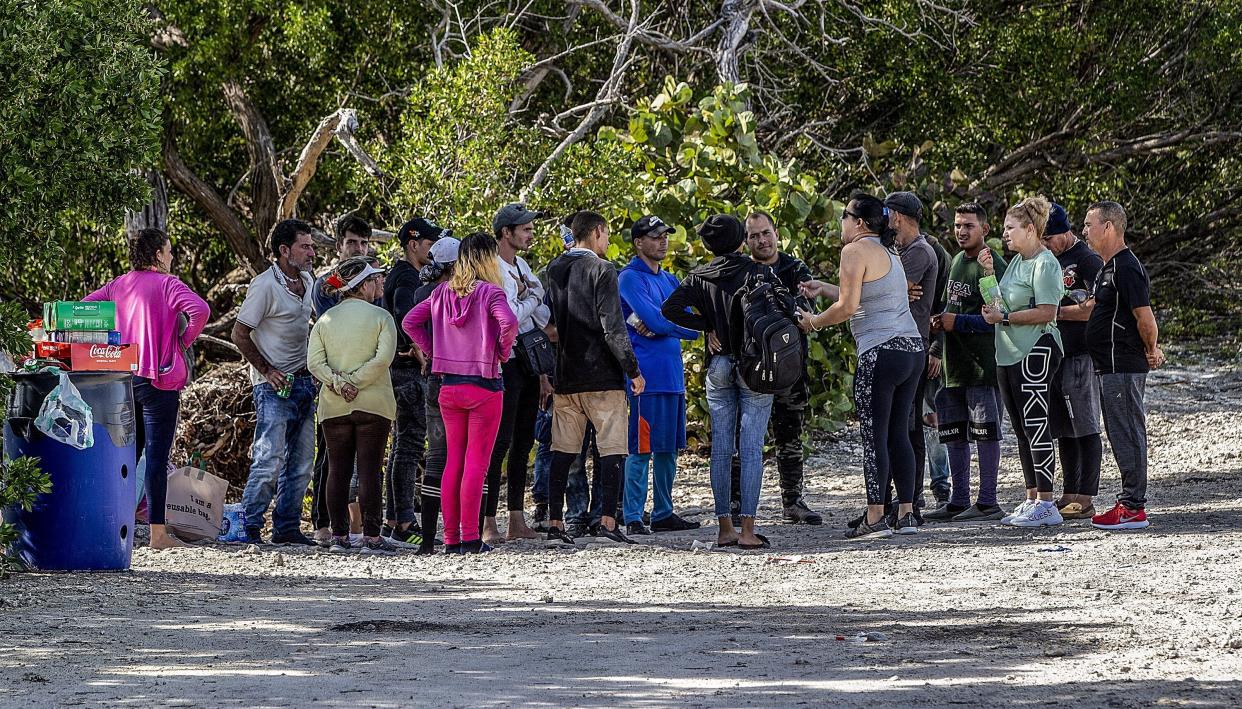 A group of Cuban migrants stand in the sun on the side of U.S. 1 in the Middle Keys island of Duck Key, Fla., Monday Jan. 2, 2023. (Pedro Portal/Miami Herald via AP)