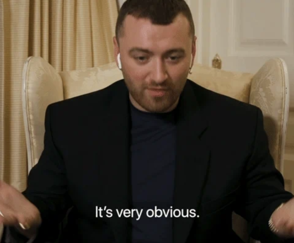 Sam Smith sitting in a chair, wearing a dark blazer and wireless earbuds, with the subtitle "It's very obvious."