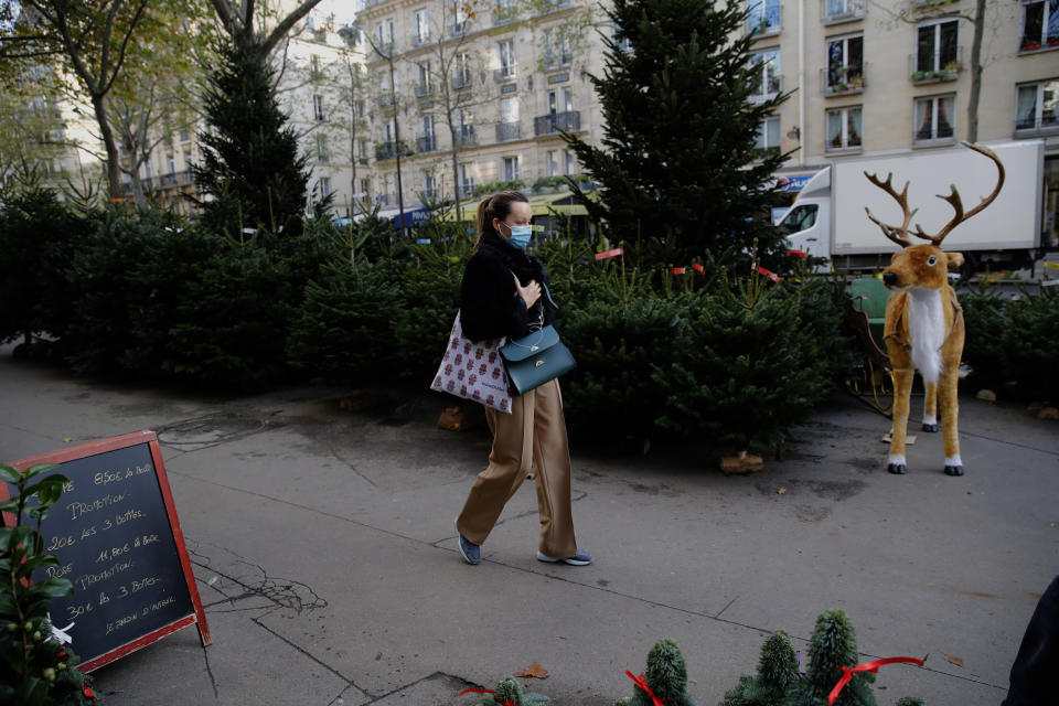 A woman walks past Christmas trees at florist in Paris on Friday. The number of new coronavirus infections in France rose by 17,881 on Saturday, lower than the 22,882 reported on Friday, while the number of people hospitalized with COVID-19 dropped for the fifth day in a row. (Photo: ASSOCIATED PRESS)