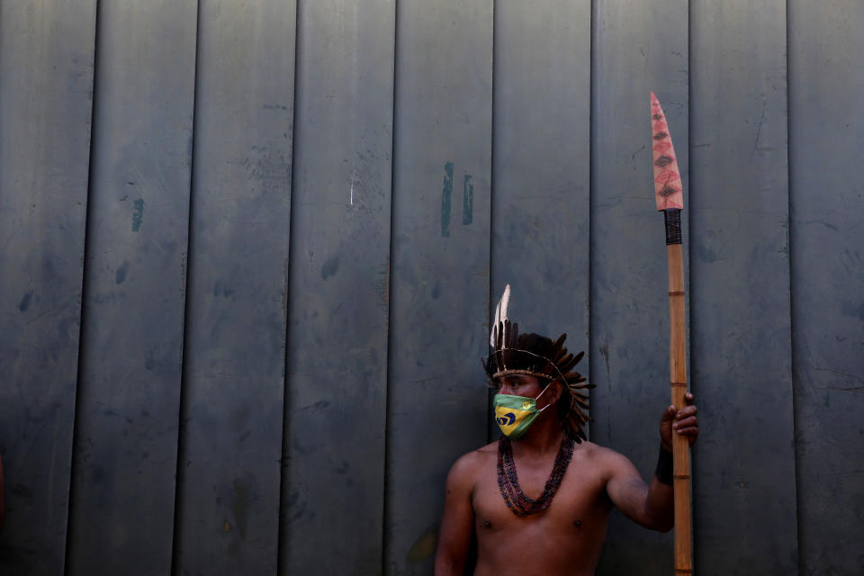 An Indigenous man wearing a protective face mask amid the COVID-19 pandemic takes part in a protest against Brazilian President Jair Bolsonaro's proposals to allow mining on Indigenous lands, at the main entrance to the Chamber of Deputies in Brasilia, Brazil, Wednesday, June 9, 2021. (AP Photo/Eraldo Peres)