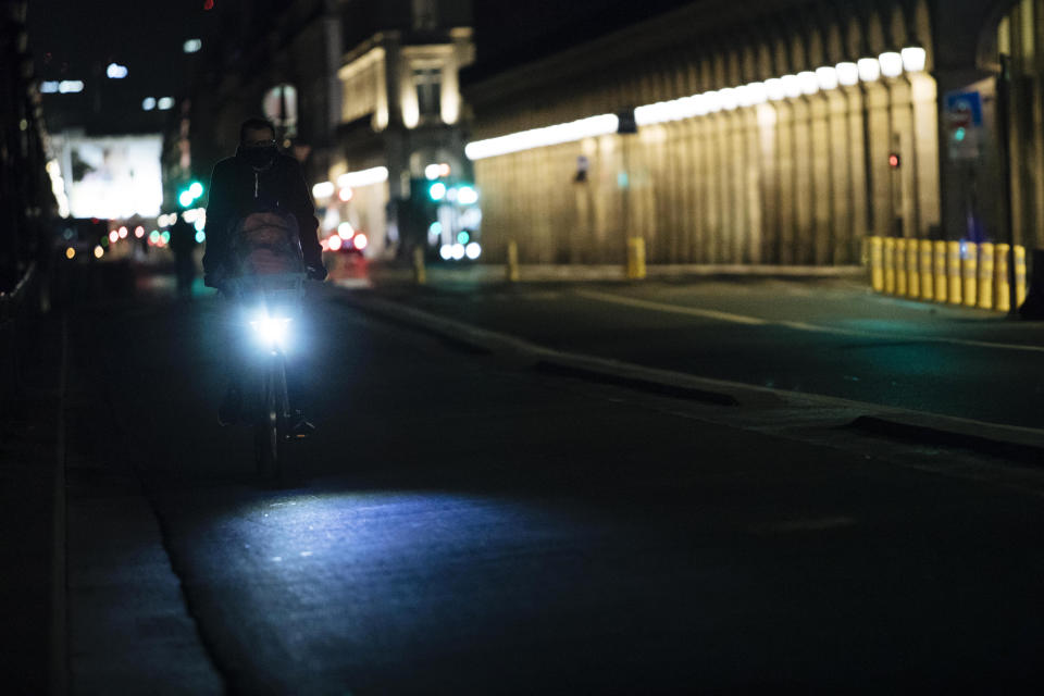 A man rides a bike on Rivoli street during curfew in Paris, Saturday, Oct. 17, 2020. French restaurants, cinemas and theaters are trying to figure out how to survive a new curfew aimed at stemming the flow of record new coronavirus infections. The monthlong curfew came into effect Friday at midnight, and France is deploying 12,000 extra police to enforce it. (AP Photo/Lewis Joly)