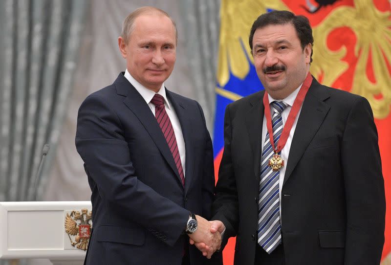 Russian President Vladimir Putin shakes hands with Rector of the Russian Presidential Academy of National Economy and Public Administration Vladimir Mau in Moscow