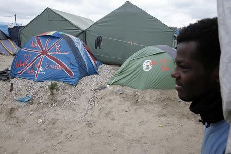 A migrant walks past tents in what is known as the "Jungle", a sprawling camp in Calais, France, October 12, 2016. REUTERS/Pascal Rossignol