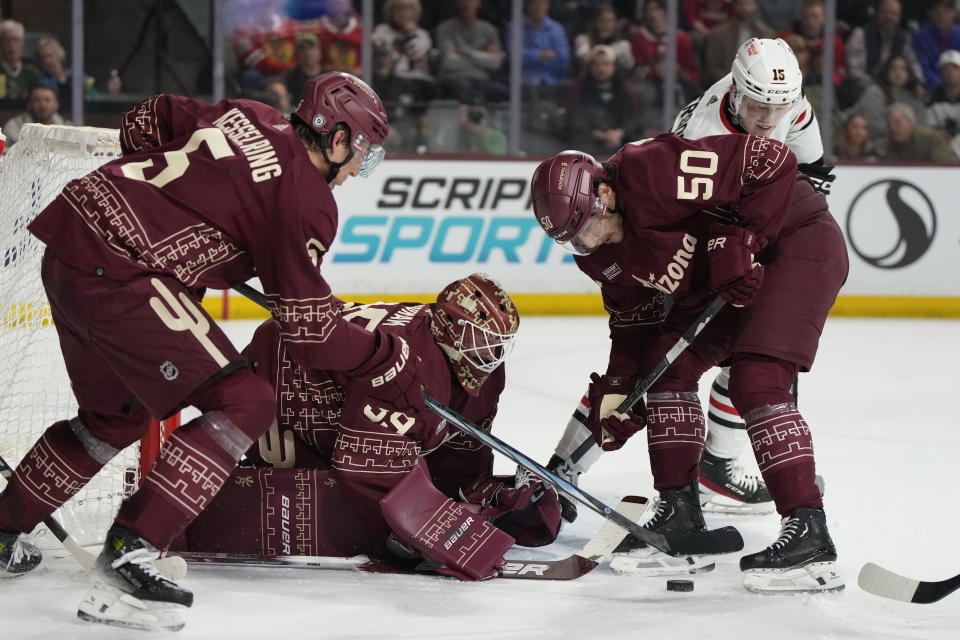 Arizona Coyotes goaltender Connor Ingram (39), defenseman Michael Kesselring (5), and defenseman Sean Durzi try to cover the puck in front of Chicago Blackhawks right wing Joey Anderson (15) in the second period during an NHL hockey game, Tuesday, March 5, 2024, in Tempe, Ariz. (AP Photo/Rick Scuteri)