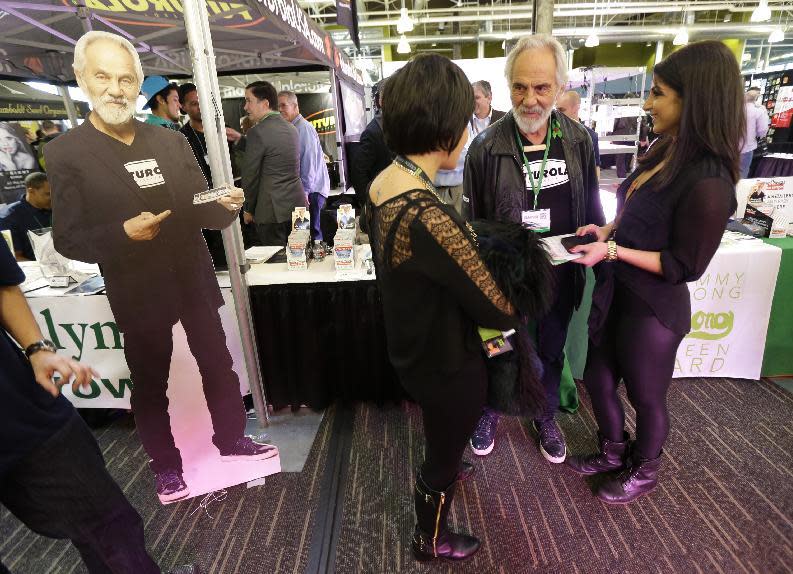 FILE - In this Feb. 19, 2015, file photo, comedian and marijuana icon Tommy Chong, second from right, talks to visitors as he stands near a life-sized cardboard cut-out of himself, while promoting his line of marijuana products during CannaCon, a marijuana business trade show in Seattle. Country singer Willie Nelson, the children of the late reggae icon Bob Marley and comedian Whoopi Goldberg are just a few of the growing number of celebrities publicly jumping into the marijuana industry and eyeing the California pot market. (AP Photo/Ted S. Warren, File)