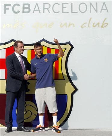 Brazilian soccer player Neymar (R) shakes hands with Barcelona's president Sandor Rosell after signing a five-year contract with FC Barcelona, in front of their offices close to Camp Nou stadium in Barcelona in this June 3, 2013 file photo. REUTERS/Albert Gea