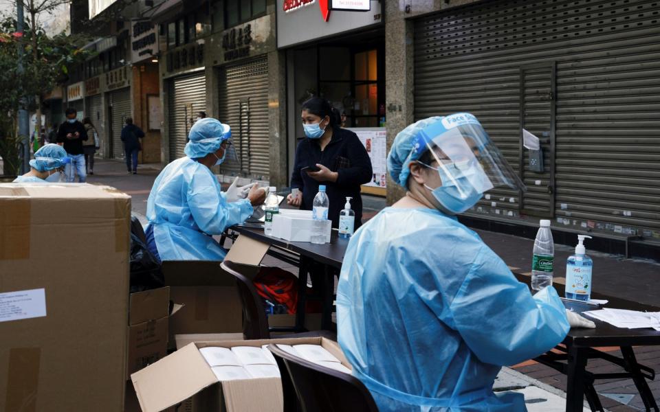 A medical worker in a protective suit helps a resident to register at a makeshift community testing centre at Jordan residential area, in Hong Kong - EUTERS/Tyrone Siu