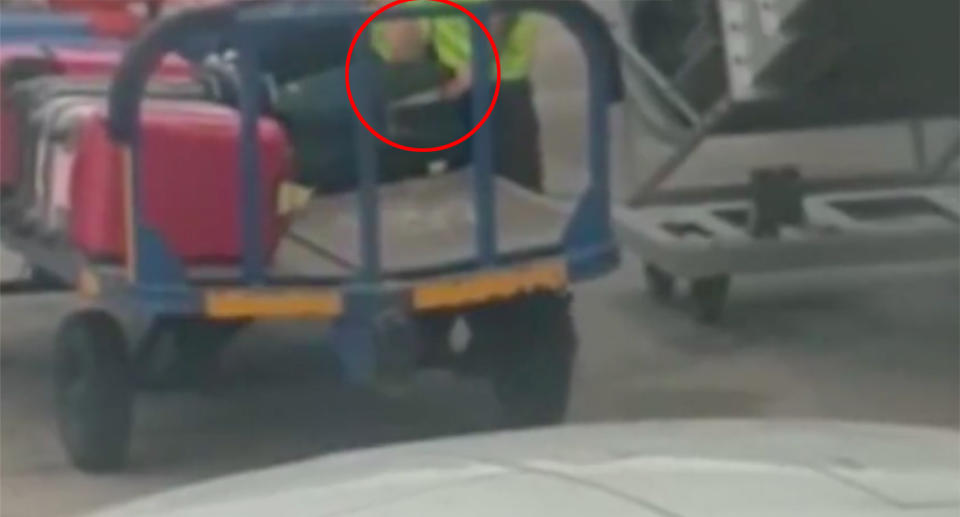 Footage shows the baggage handler unzip a suitcase which is on a luggage trolley before digging around inside it. Source: Diario de Ibiza