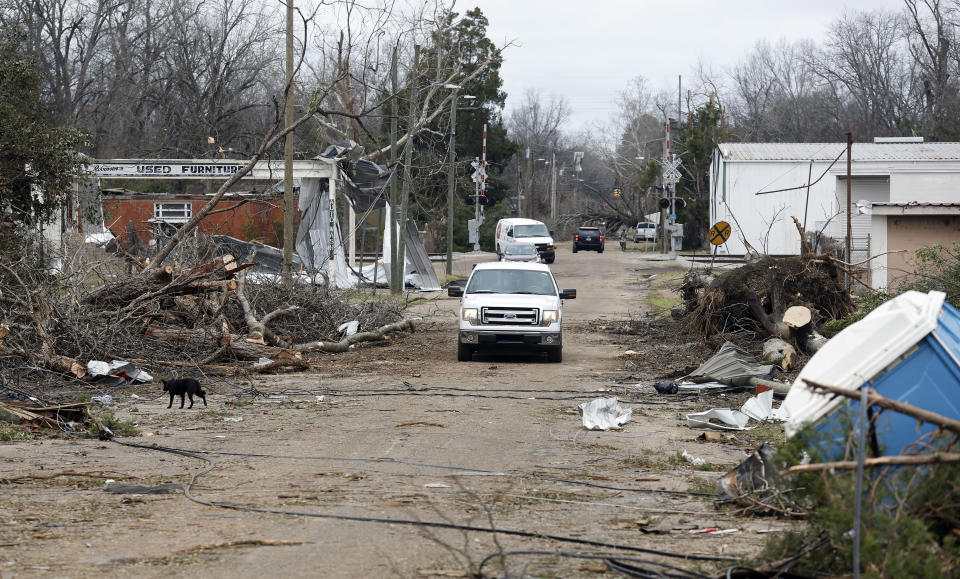 Vehicles navigate a road strewn with debris in Selma, Ala., Friday, Jan. 13, 2023, after a tornado passed through the area. Rescuers raced Friday to find survivors in the aftermath of a tornado-spawning storm system that barreled across parts of Georgia and Alabama. (AP Photo/Stew Milne)