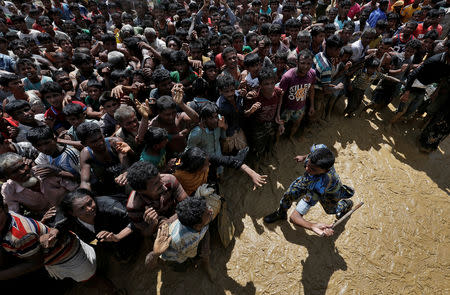 FILE PHOTO: A security officer attempts to control Rohingya refugees waiting to receive aid in Cox's Bazar, Bangladesh, September 21, 2017. REUTERS/Cathal McNaughton/File Photo