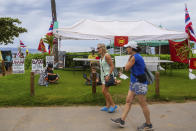 Tourists pass by the "Fish-in" camp on the popular beach of Kaanapali Beach, Friday, Dec. 1, 2023, in Lahaina, Hawaii. Lahaina Strong has set up a "Fish-in" to protest living accommodations for those displaced by the Aug. 8, 2023 wildfire, the deadliest U.S. wildfire in more than a century. More than four months after the fire, tensions are growing between those who want to welcome tourists back to provide jobs and those who feel the town isn't ready for a return to tourism." (AP Photo/Ty O'Neil)