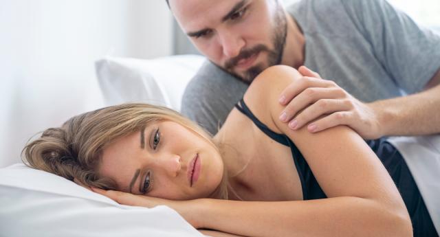 Woman looks upset in bed as man comforts her. (Getty Images)