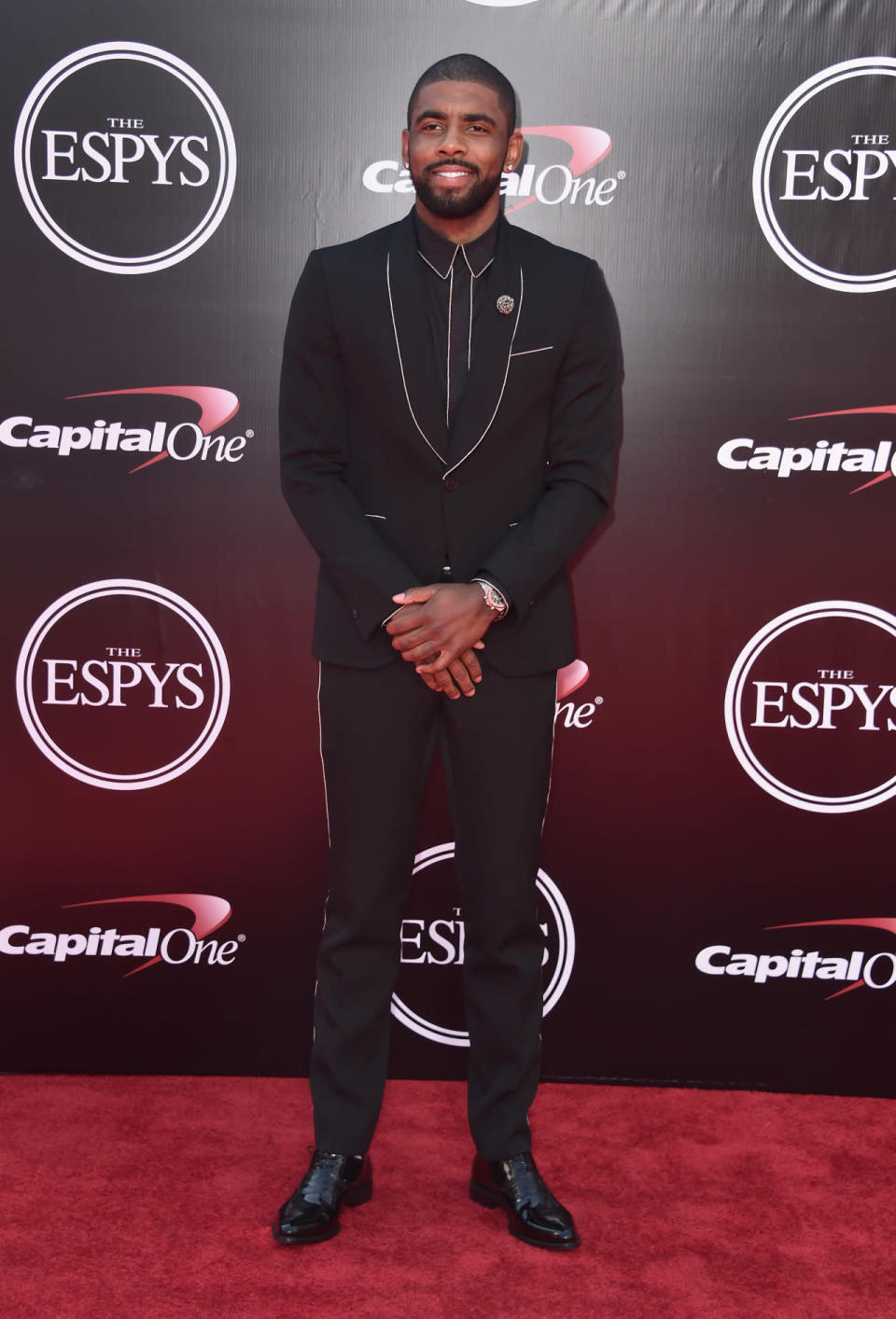 Kyrie Irving in a black suit with white piping 