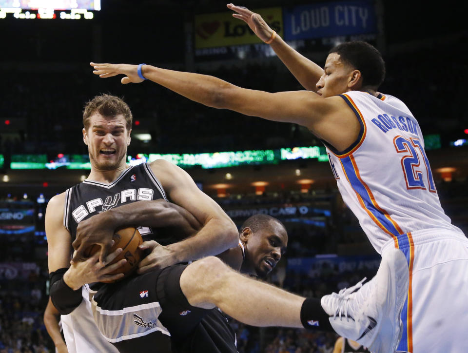 San Antonio Spurs center Tiago Splitter fights for control of the ball with Oklahoma City Thunder forward Serge Ibaka in front of Thunder forward Andre Roberson (21) during the third quarter of an NBA basketball game in Oklahoma City, Thursday, April 3, 2014. Oklahoma City won 106-94. (AP Photo/Sue Ogrocki)