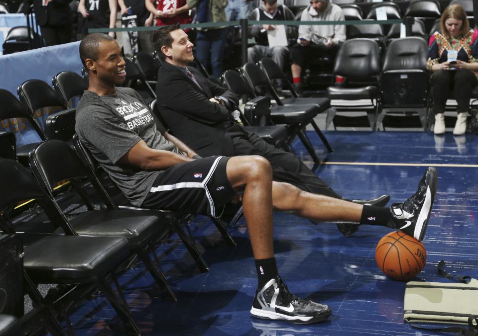 Brooklyn Nets center Jason Collins sits in a courtside seat after warming up for the Nets' NBA basketball game against the Denver Nuggets in Denver on Thursday, Feb. 27, 2014. (AP Photo/David Zalubowski)
