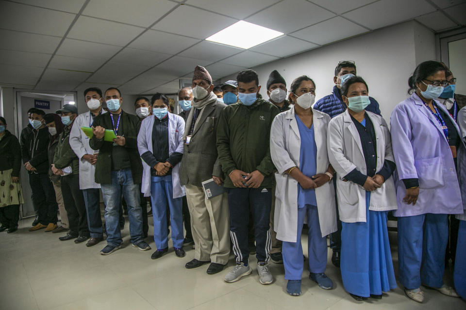 Nepalese health workers observe a minute of silence in memory of people who died due to COVID-19 before administering vaccine at Teaching Hospital in Kathmandu, Nepal, Wednesday, Jan. 27, 2021. Thousands of health workers lined up across Nepal to get the coronavirus vaccine Wednesday as the Himalayan nation began its campaign to get the population vaccinated within three months. Neighboring India gifted Nepal 1 million doses of the AstraZeneca-Oxford University vaccine manufactured under license by the Serum Institute of India. (AP Photo/Niranjan Shrestha)