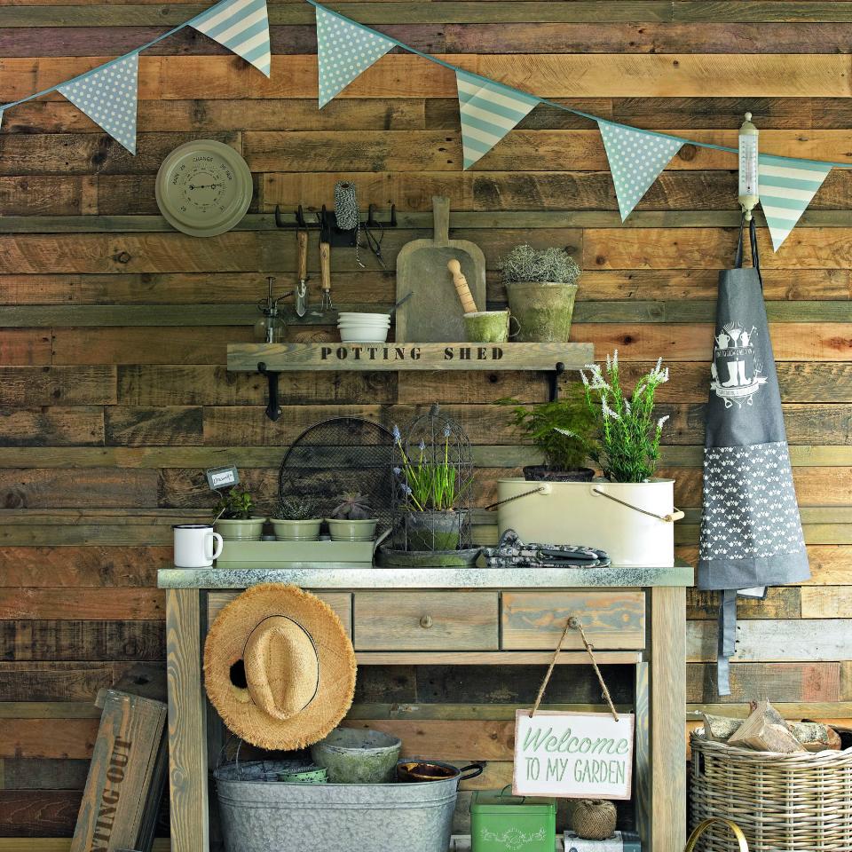 A gardening table with a hat, an apron and a bunting above it