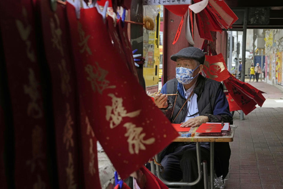 Chan King-fat, 80-year-old calligraphy artist writes "Fai Chun," traditional decorations with Chinese calligraphy in Hong Kong on Jan. 27, 2022. In the runup to the Lunar New Year, calligraphers set up on the streets of Hong Kong to write ink-brush phrases on traditional red paper banners for homes and offices. (AP Photo/Kin Cheung)