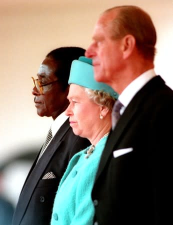 FILE PHOTO: Queen Elizabeth II and the Duke of Edinburgh stand with the President of Zimbabwe, Robert Mugabe, shortly before he reviewed a guard of honour in London