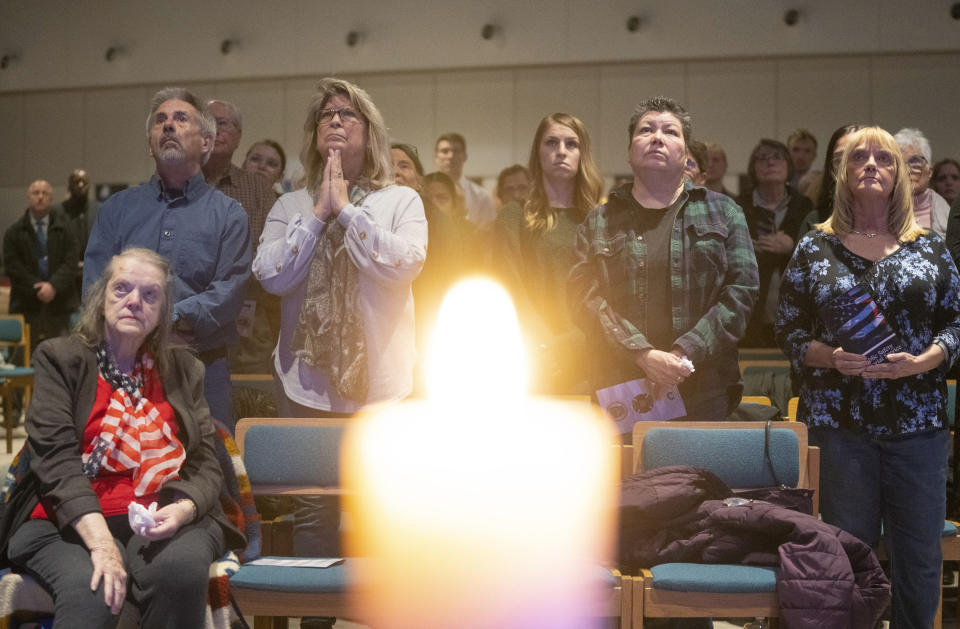 FILE - Mourners listen to the playing of "Amazing Grace" on a live stream of a memorial service for Burnsville police officers Paul Elmstrand and Matthew Ruge and firefighter-paramedic Adam Finseth at Prince of Peace in Burnsville, Minn., Feb. 28, 2024. A woman has been charged with illegally buying guns used in the killings of the three Minnesota first responders in a standoff at a home in Burnsville, where seven children were inside, U.S. Attorney Andrew M. Luger announced Thursday, March 14, at a news conference. (Alex Kormann/Star Tribune via AP, File)
