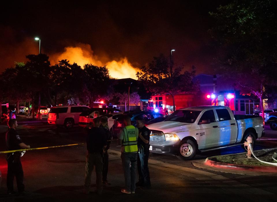 Fire crews and safety officials tackle the wildfire that spread to an apartment complex in Cedar Park on Tuesday night. The fire destroyed one building at complex and damaged two others, officials said.