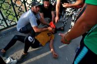 An Iraqi man receives first aid after Iraqi security forces fired tear gas during anti-government protests in Baghdad, Iraq, Sunday, Oct. 25, 2020. Protesters marched Sunday in the capital and several southern cities to renew demands to bring an end to corruption perpetuated by Iraq's politicians. (AP Photo/Khalid Mohammed)