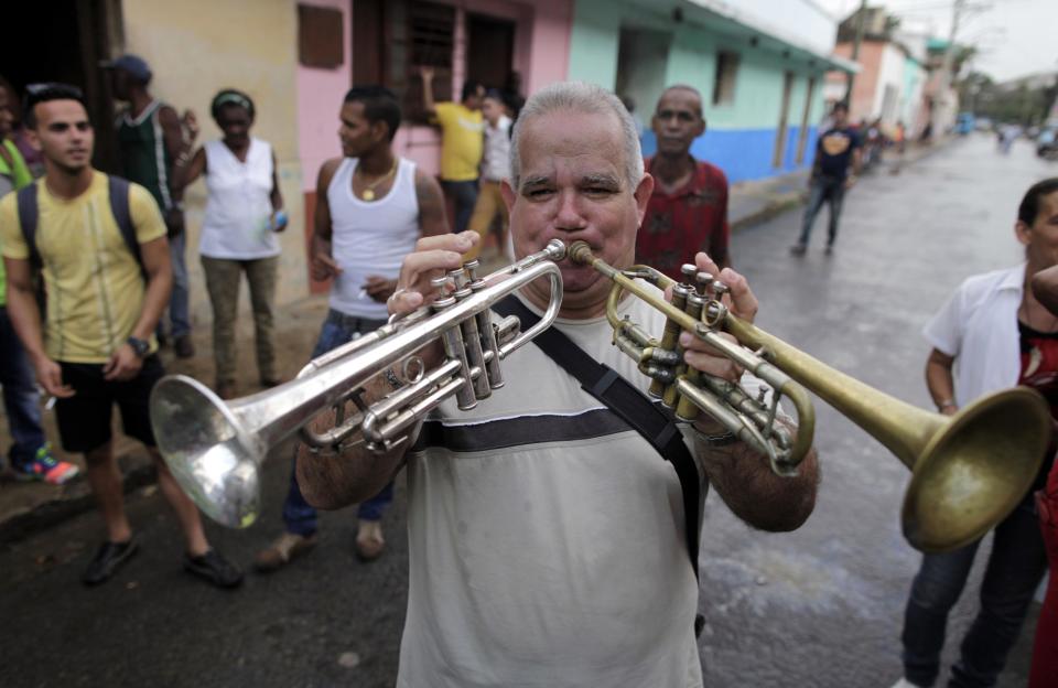 In this Feb. 5, 2014 photo, Carlos Pineiro plays two trumpets during the celebration of a mock funeral known as the Burial of Pachencho in Santiago de Las Vegas, Cuba. The tradition was born on Feb. 5, 1984, when villagers got the idea of putting on a mock burial to mark the end of local carnival season. It took its name from the title of a play that had showed in what was then the town theater. (AP Photo/Franklin Reyes)