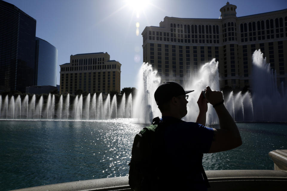 FILE - In this April 15, 2015 file photo, a man takes a picture of the fountains in front of the Bellagio hotel and casino in Las Vegas. State lawmakers on Monday, March 13, 2023, are scheduled to discuss granting the power to limit what comes out of residents’ taps to the Southern Nevada Water Authority, the agency managing the Colorado River supply to the city. (AP Photo/John Locher, File)