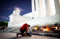 A man kneels as he brings a megaphone to a vigil on the steps of the U.S. Supreme Court following the death of U.S. Supreme Court Justice Ruth Bader Ginsburg, in Washington