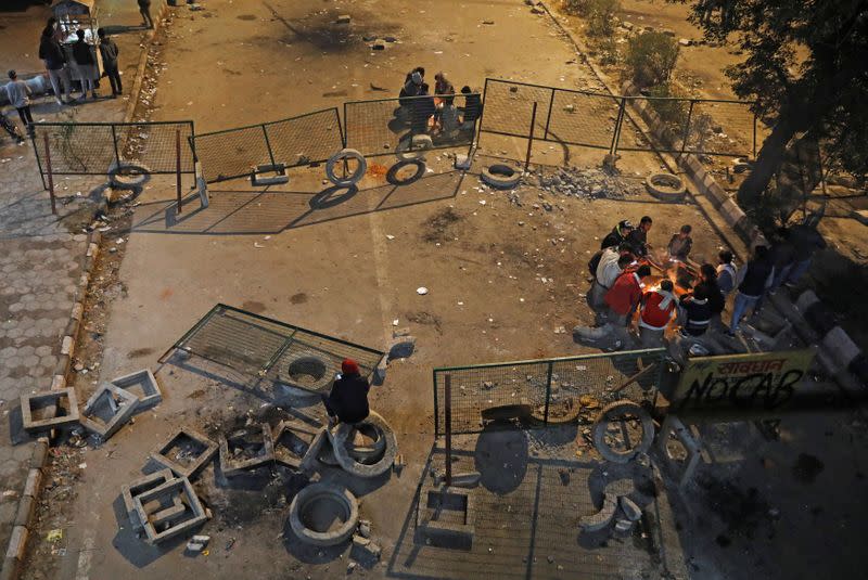 Local residents sit next to bonfires as they block a road during a protest against a new citizenship law, in New Delhi