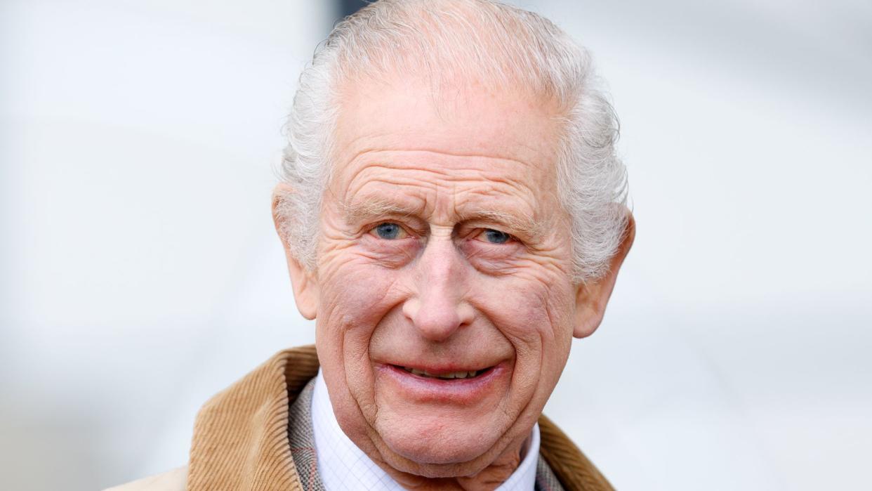 king charles smiling in beige coat and tie