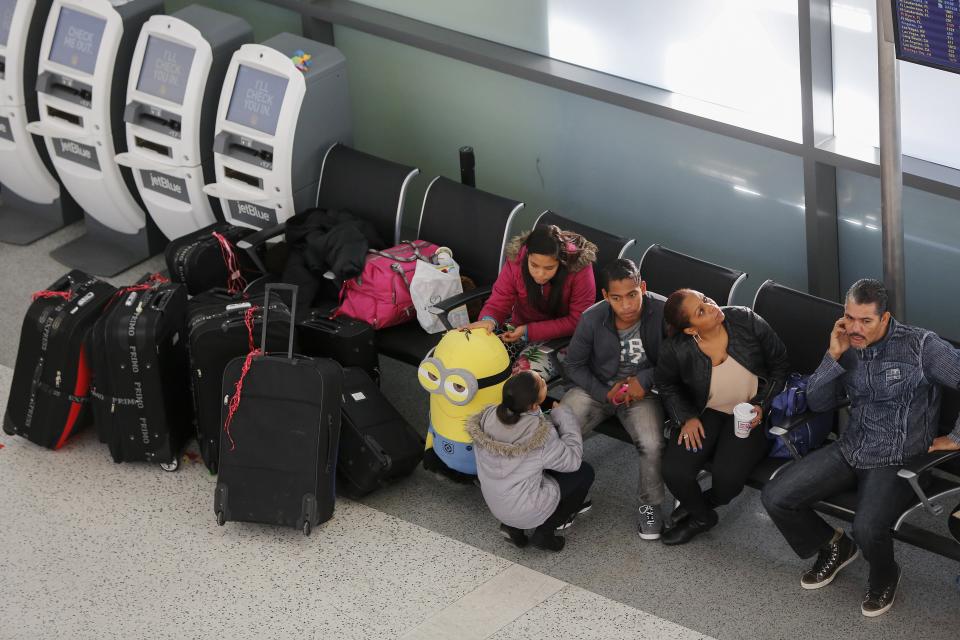 Travellers sit near their luggage inside the JetBlue Airways terminal at John F. Kennedy International Airport in New York, January 6, 2014. JetBlue Airways said it planned to suspend flights at New York and Boston airports later on Monday, and gradually resume them on Tuesday, as extreme cold hobbled airline operations in the U.S. Midwest and Northeast regions. REUTERS/Shannon Stapleton (UNITED STATES - Tags: TRANSPORT ENVIRONMENT)