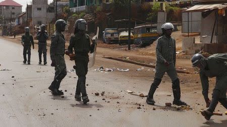 Security forces walk down a street filled with debris after protests in Conakry, Guinea, May 7, 2015. REUTERS/Saliou Samb