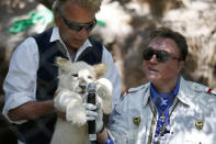 Siegfried Fischbacher, left, holds up a white lion cub as Roy Horn holds up a microphone during an event to welcome three white lion cubs to Siegfried & Roy's Secret Garden and Dolphin Habitat, Thursday, July 17, 2014, in Las Vegas. The three white lion cubs, born in South Africa, are scheduled to be available for public viewing Friday. (AP Photo/John Locher)