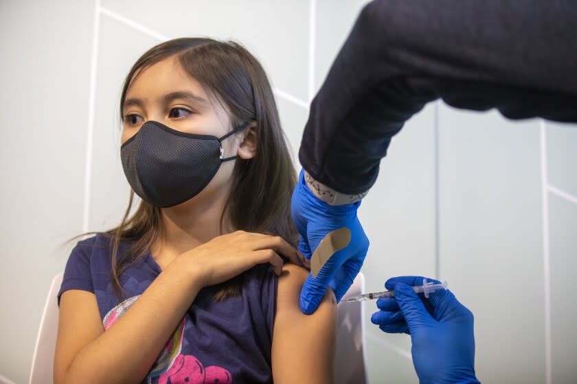 TUSTIN, CA - NOVEMBER 04: Kailyn Nguyen 9, left, receives a vaccination from Christopher King, 31, LVN right, at Kaiser Permanente Tustin Ranch Vaccination Clinic on Thursday, Nov. 4, 2021 in Tustin, CA. Following FDA and CDC approval of the Pfizer COVID-19 vaccine for younger children, Kaiser Permanente health care professionals will administer the first of two shots to six children ranging in age between 5-11 to protect them against contracting Covid-19. (Francine Orr / Los Angeles Times)