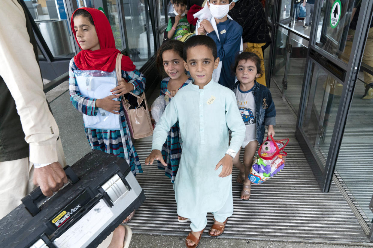 Children accompanied by their families evacuated from Kabul, Afghanistan, walk through the terminal before boarding a bus after they arrived at Washington Dulles International Airport, in Chantilly, Va., on Thursday, Aug. 26, 2021. (AP Photo/Jose Luis Magana)