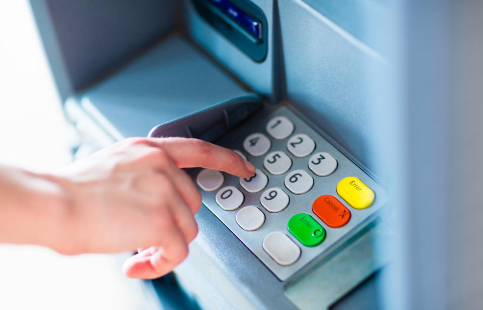 Close-up of hand entering PIN/pass code for a money transfer, on a ATM/bank machine keypad outside