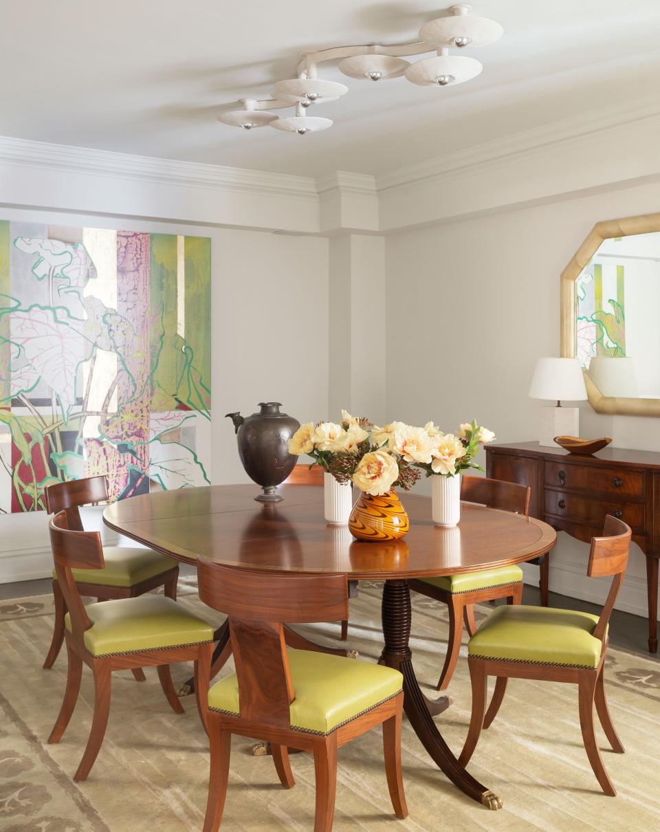Flashes of bright green in the dining room are a subtle way to bring nature indoors. The dining table and sideboard, antiques from the client, are paired with vinyl-upholstered dining chairs from the Huniford Collection. The light fixture is a custom piece by Stephen Antonson.