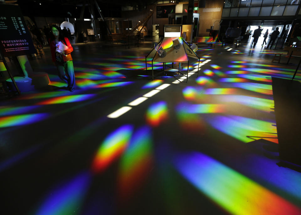 Quynh Tran, left, looks over the colored reflections cast on the floor of the central gallery at the Exploratorium, an interactive science and activities museum, during a preview in San Francisco, Tuesday, April 9, 2013. The new $300 million museum is set to open April 17 at its new location along the bay with more space and new exhibits. The 330,000-square-foot museum at Pier 15 along the Embarcadero has three times more space than the previous location at the Palace of Fine Arts in the city's Marina neighborhood. (AP Photo/Eric Risberg)