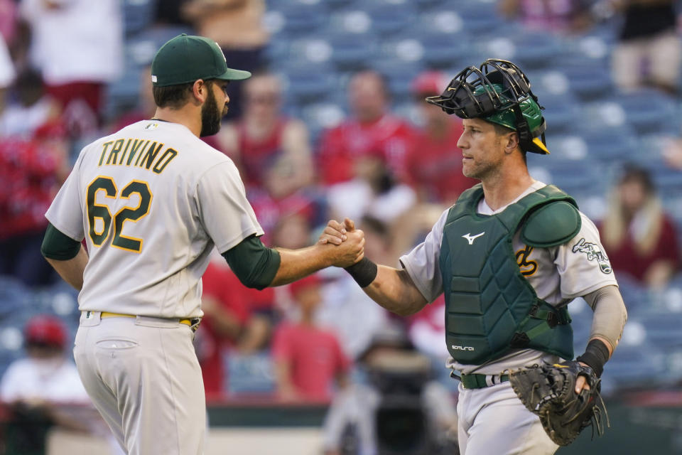 Oakland Athletics relief pitcher Lou Trivino, left, and catcher Yan Gomes celebrate a win in the 10th inning of a baseball game against the Los Angeles Angels, Sunday, Sept. 19, 2021, in Anaheim, Calif. (AP Photo/Jae C. Hong)