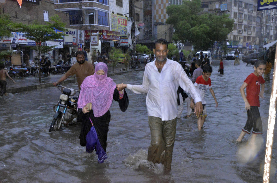 CORRECTS LOCATION TO HYDERABAD NOT KARACHI AND BYLINE TO PERVEZ MASIH People wade through a flooded area caused by heavy monsoon rainfall in Hyderabad, Pakistan, Sunday, July 23, 2023. (AP Photo/Pervez Masih)