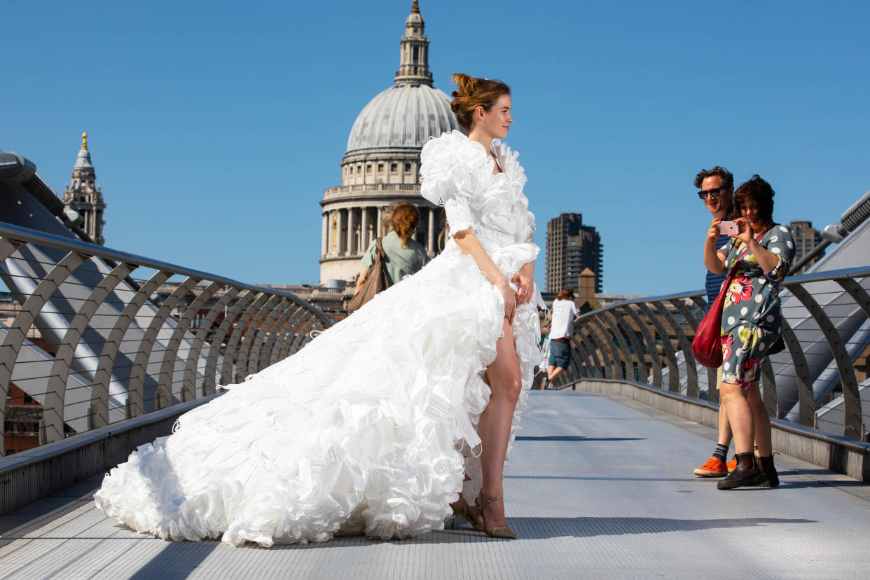 EDITORIAL USE ONLY Jemima Hambro models, on the Millennium Bridge in London, a wedding dress designed by Tom Silverwood and made from over 1,500 unwanted face masks, for wedding planning website, Hitched, to celebrate all restrictions on weddings lifting in England from Monday. Issue date: Monday July 19, 2021.