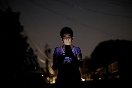 FILE PHOTO: Maria Esis, 52, a kidney disease patient, uses a telephone in front of her house during a blackout in Maracaibo, Venezuela April 11, 2019. REUTERS/Ueslei Marcelino