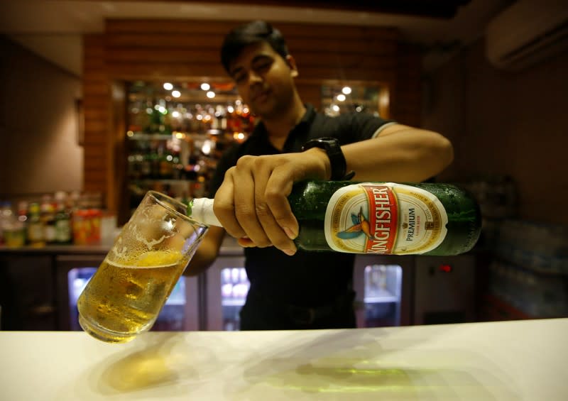 A bartender fills a glass with Kingfisher beer at a restaurant bar in Kolkata