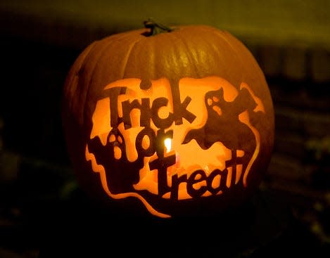 A pumpkin carving in the shape of ghosts and the words "Trick or Treat"