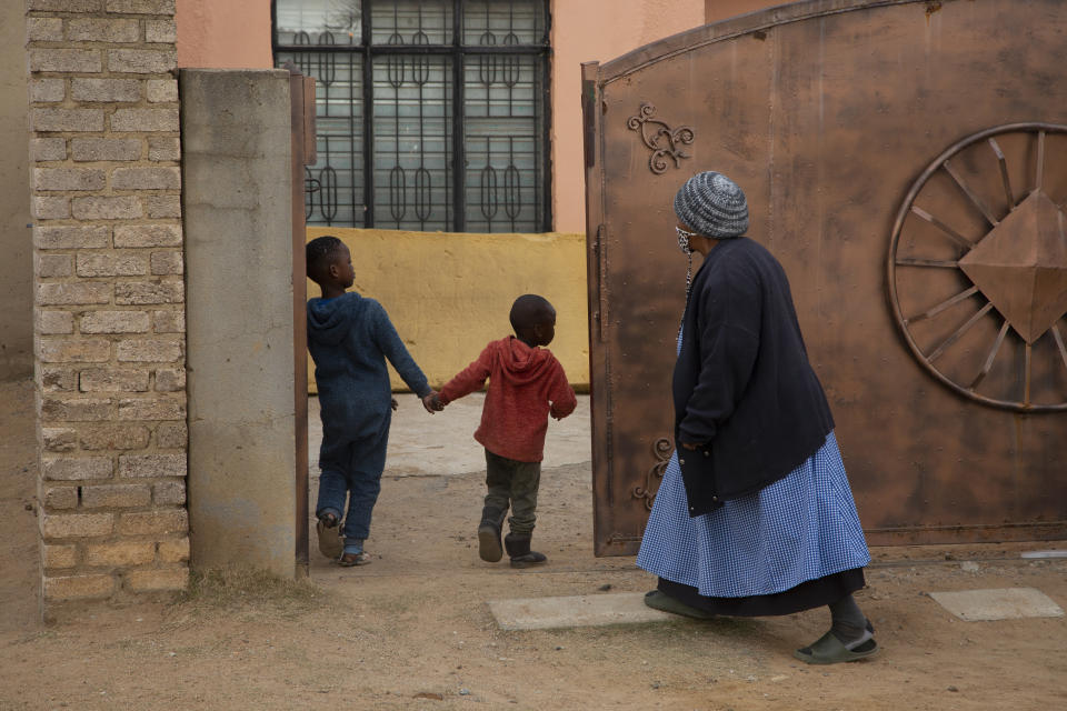 An elderly woman and children enter the property of the home of Gosiame Thamara Sithole in Tembisa, near Johannesburg Thursday June 10, 2021. South Africa is gripped by a mystery over if the woman, Sithole, has, as has been claimed, given birth to 10 babies in what would be a world-first case of decuplets. The South African government said Thursday it is still trying to verify the claim. (AP Photo/Denis Farrell)