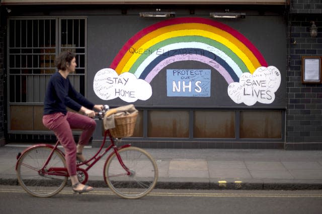 A woman cycling past a rainbow graffiti in support of the NHS in Soho, central London (Victoria Jones/PA)