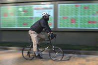 A man cycle pasts by an electronic stock board of a securities firm in Tokyo, Tuesday, Dec. 3, 2019. Asian shares slipped Tuesday, following a drop on Wall Street amid pessimism over U.S.-China trade tensions. (AP Photo/Koji Sasahara)