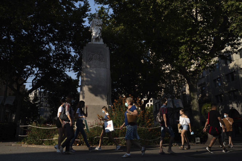 People walk past the statue of Spanish aristocrat Joan Güell in the Gran Via avenue Barcelona, Spain, Thursday, July 2, 2020. Unlike in the United States, Britain and Belgium, statues of colonial-era figures have not become a major source of protests in Spain, which once ruled over one of the largest empires in history after conquering much of the Americas. Barcelona Mayor Ada Colau is one of the few public officials who say Spain must revisit its colonial legacy - though she is against timid calls to remove the city’s monument to Christopher Columbus. (AP Photo/Renata Brito)